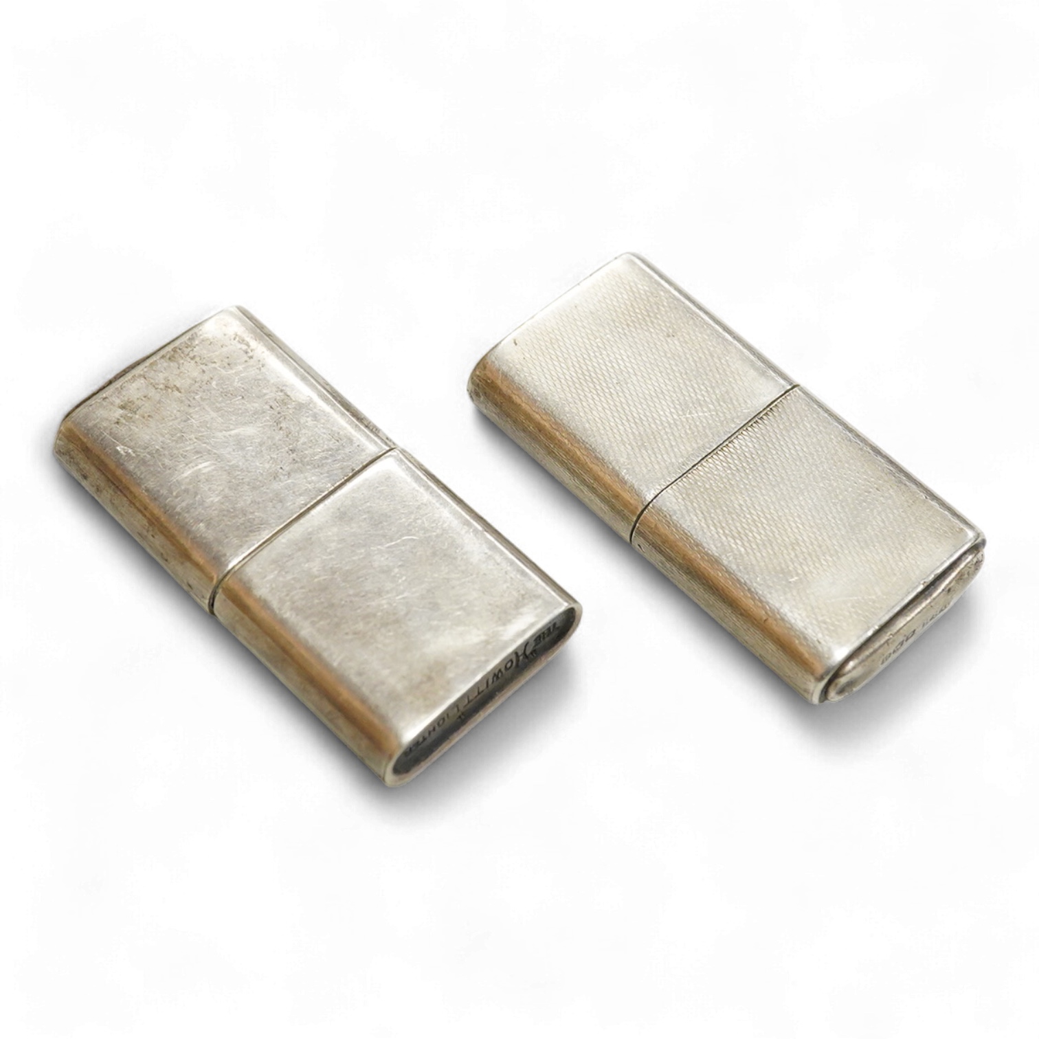 A near pair of George VI silver mounted lighters, each inscribed 'The Howitt Lighter', by Dudley Russell Howitt, Sheffield, 1946, (one engine turned), 58mm.